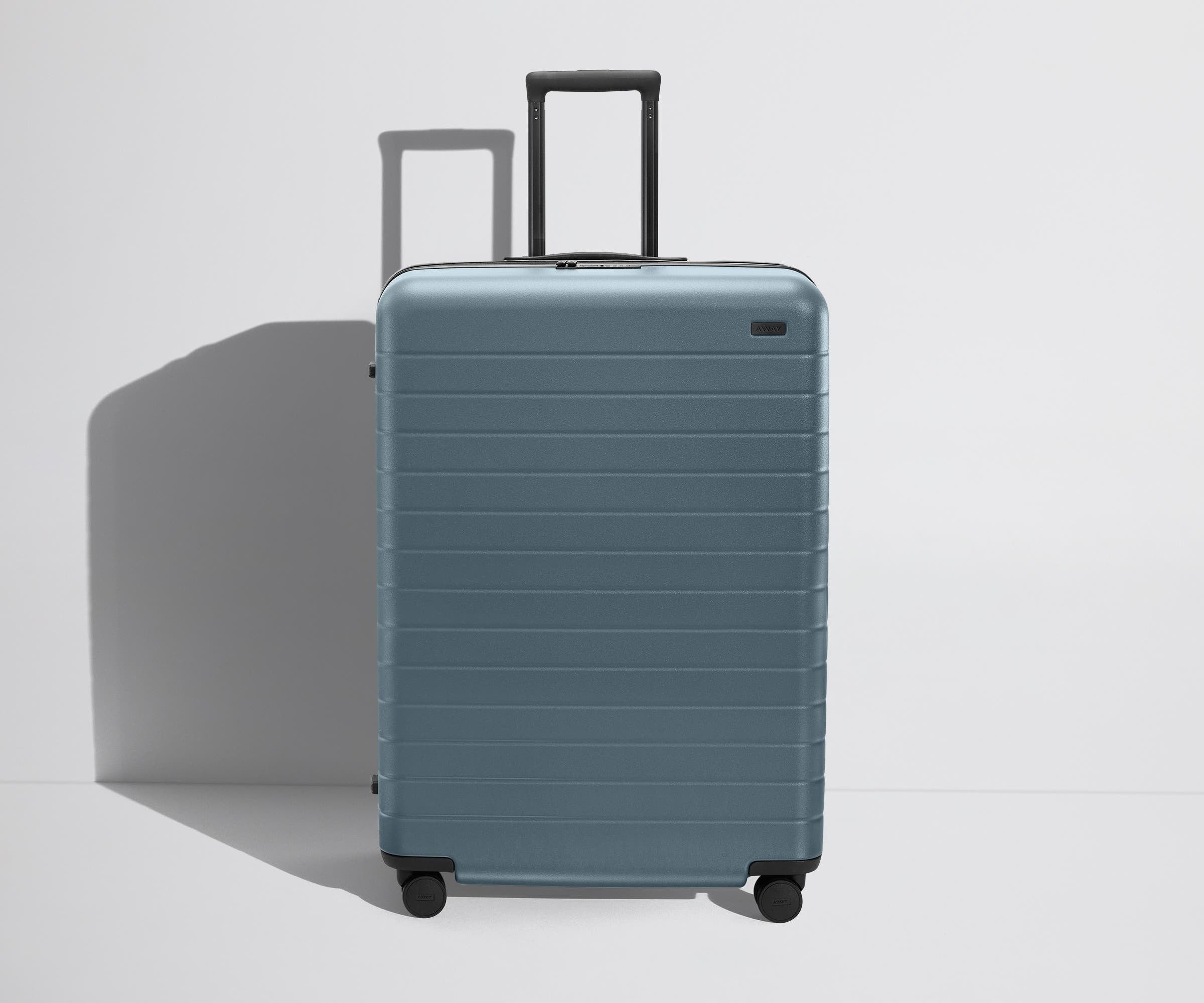 Front product view of The Large Flex suitcase in Coast Blue with raised handle