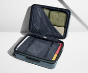 The Medium Flex suitcase in Coast Blue shown open on its side and packed with Away's packing organizers to show capacity and the interior compression system, designed to help you pack more in