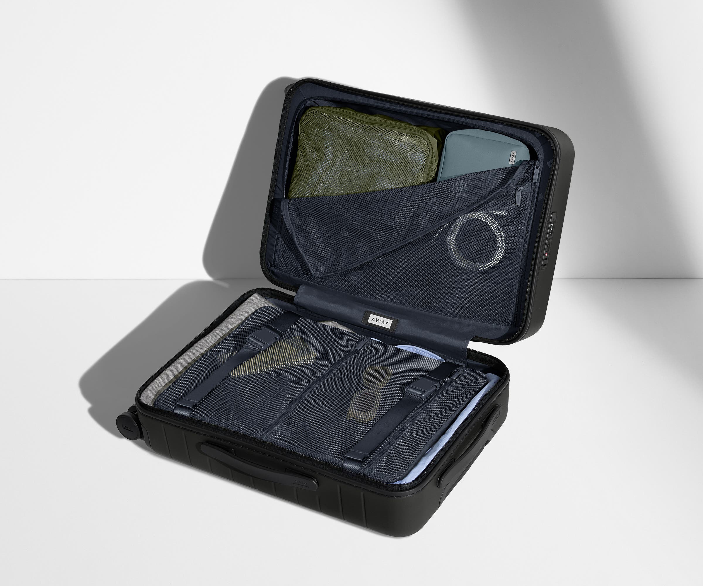 The Bigger Carry-On suitcase in Jet Black shown open on its side and packed with Away's packing organizers to show capacity and the interior compression system, designed to help you pack more in
// 
Our signature interior compression system allows you to stay more organized. Paired with The Insider Packing Cubes.