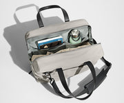 Main compartment packed with a light sweater, notebook, tablet, and water bottle. The detachable shoulder strap is clipped onto the bag.