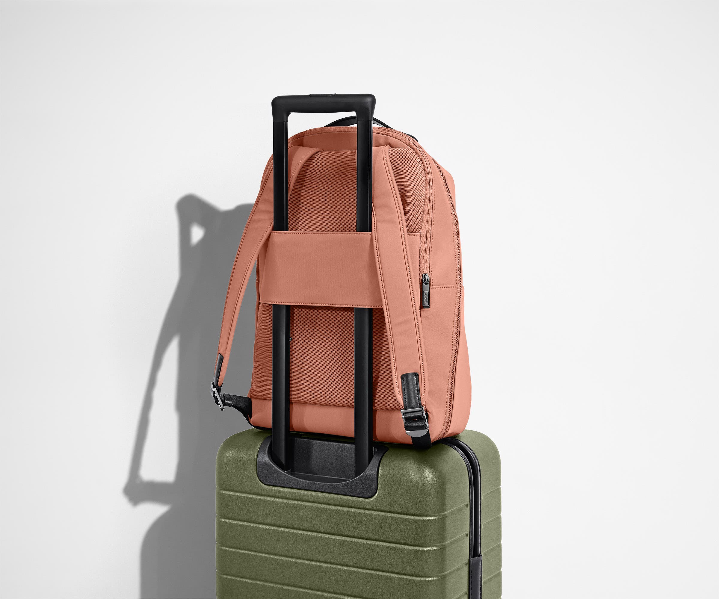 The Everywhere Zip Backpack in Clay Pink on top of an Away carry-on suitcase