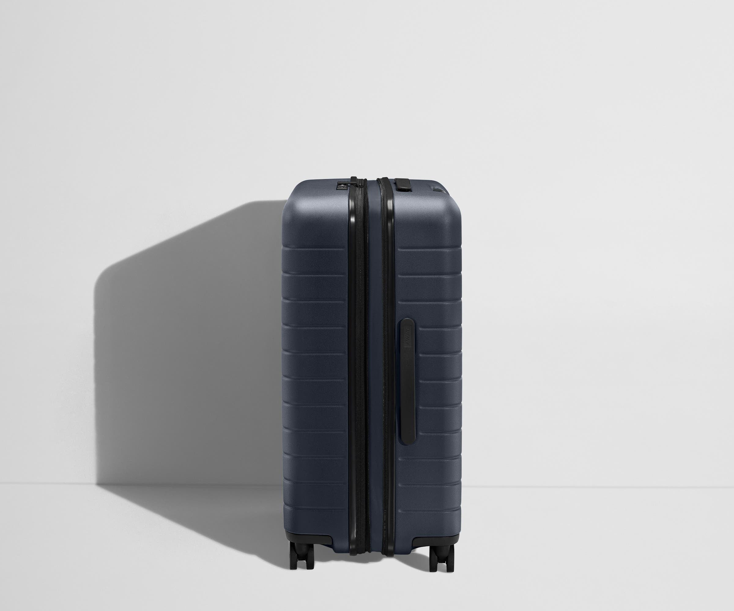 Side product view of The Medium Flex suitcase in Navy Blue shown fully expanded