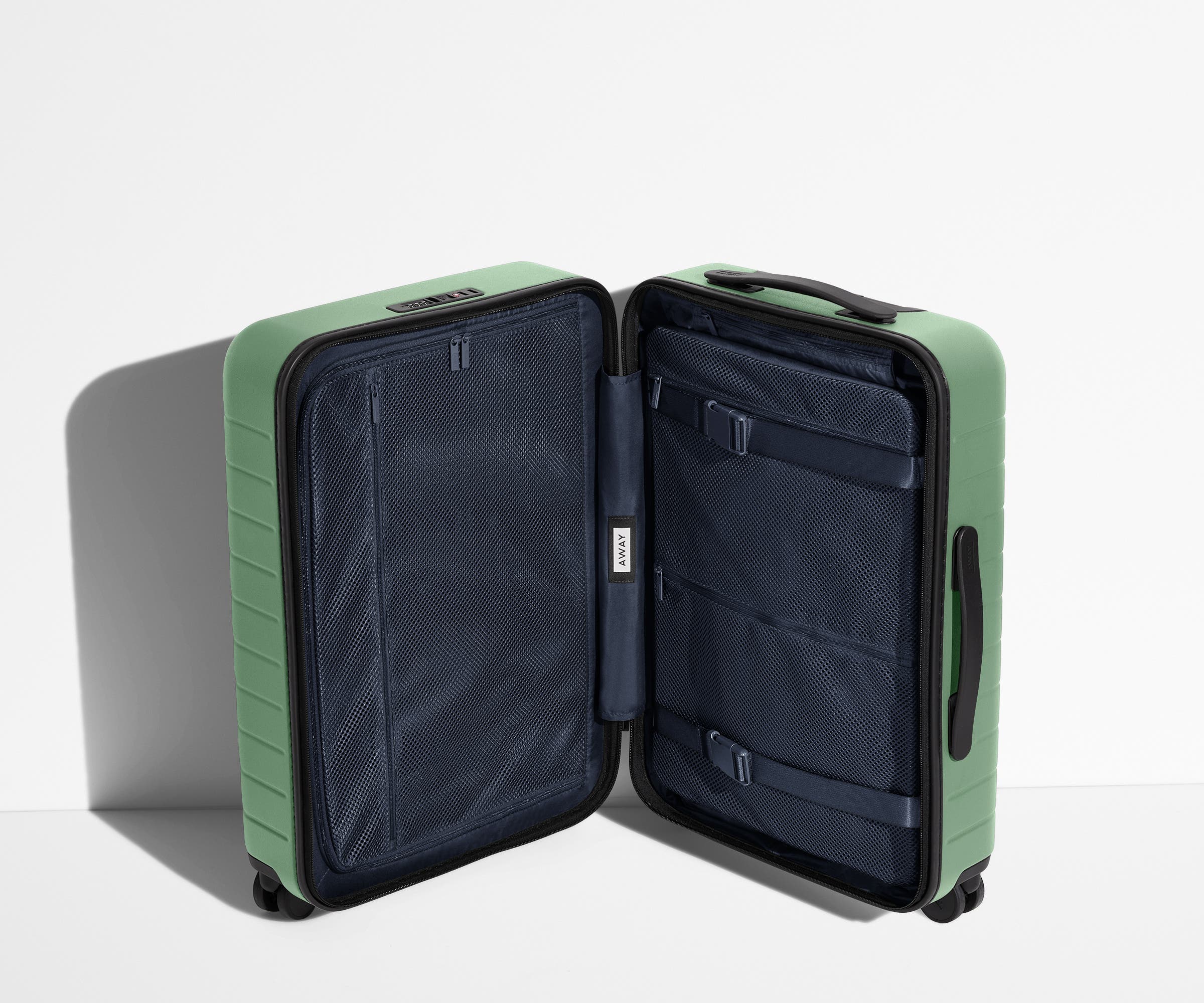 The Bigger Carry-On suitcase in Sea Green shown open in an upright position to show interior organization and compression system