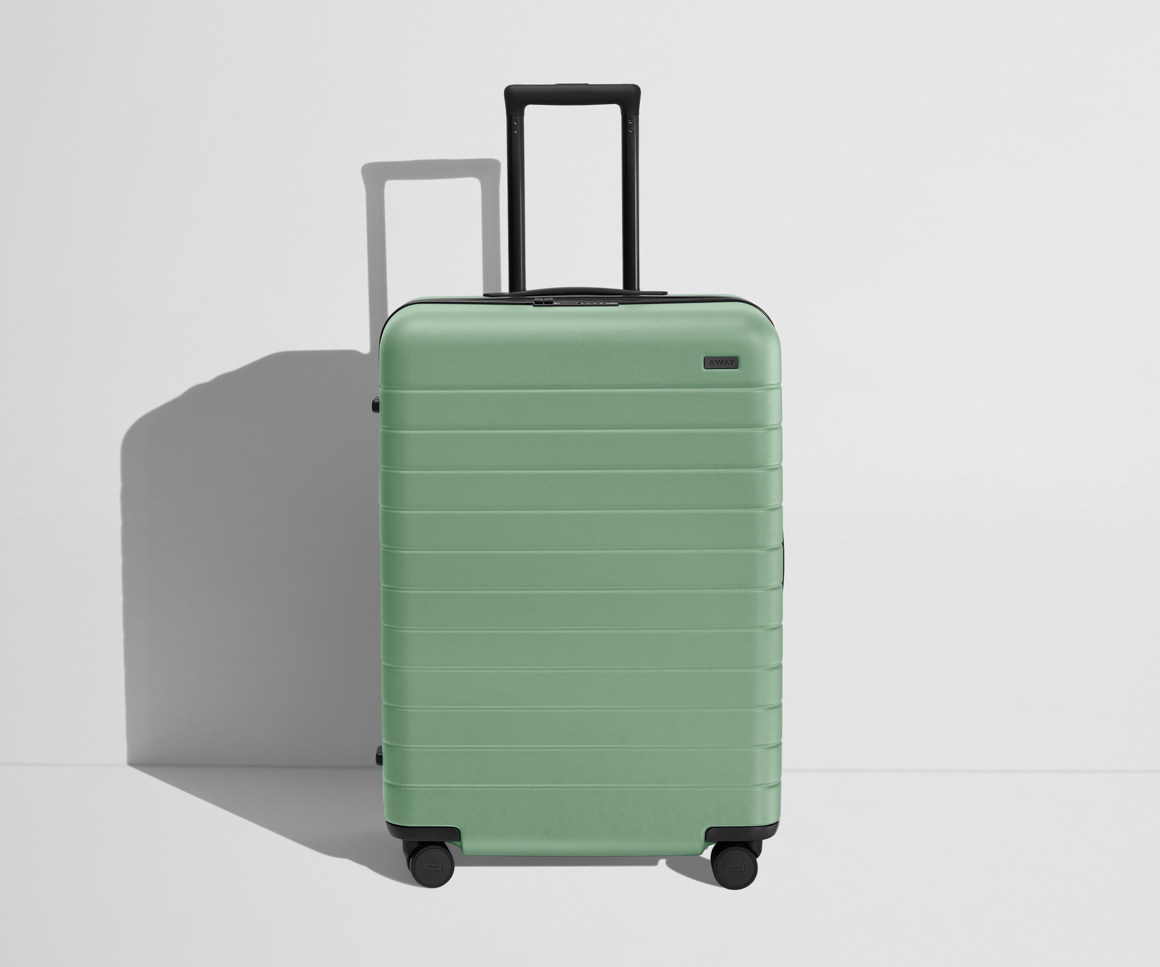 Front product view of The Medium Flex suitcase in Sea Green with raised handle