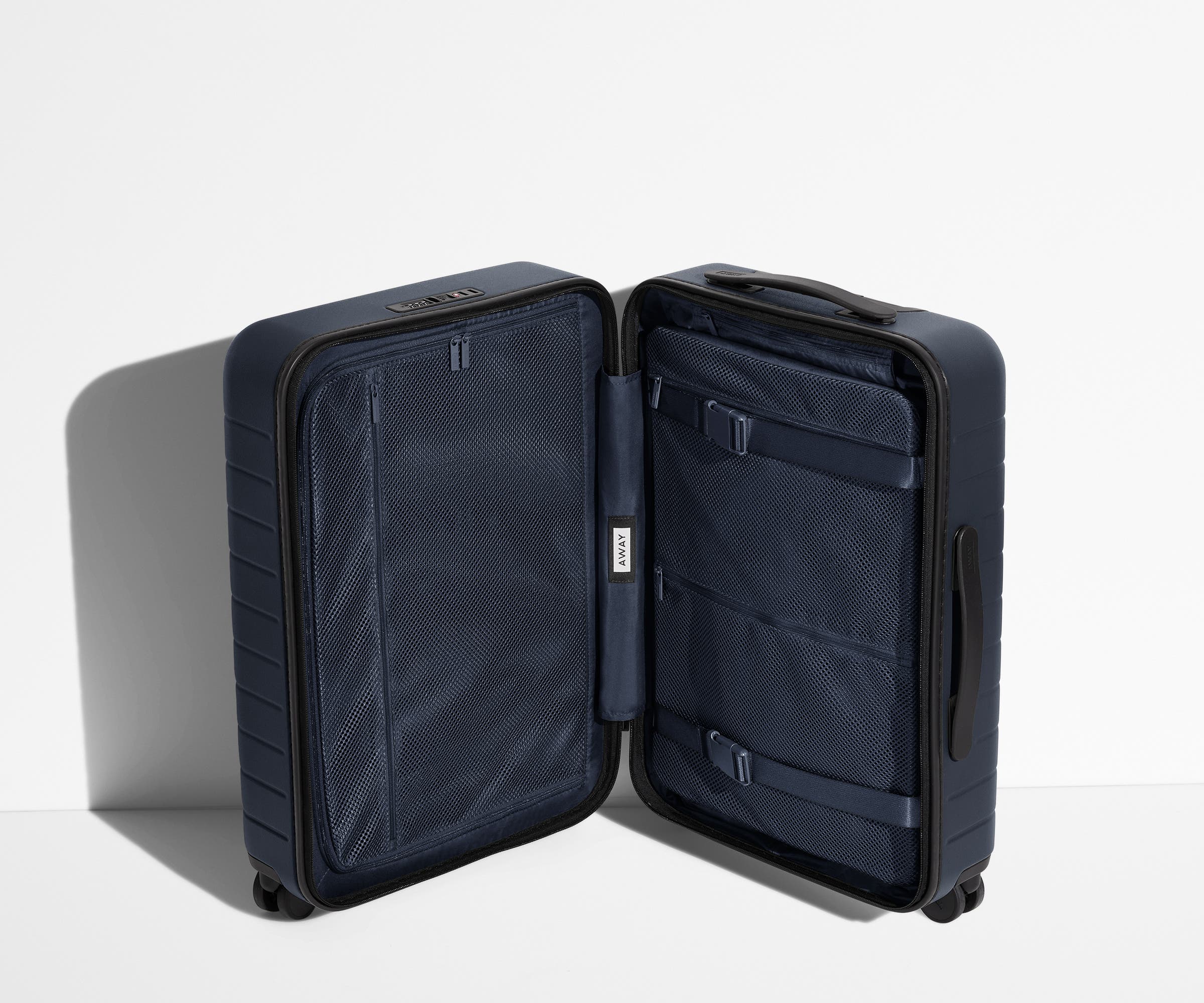 The Bigger Carry-On suitcase in Navy Blue shown open in an upright position to show interior organization and compression system