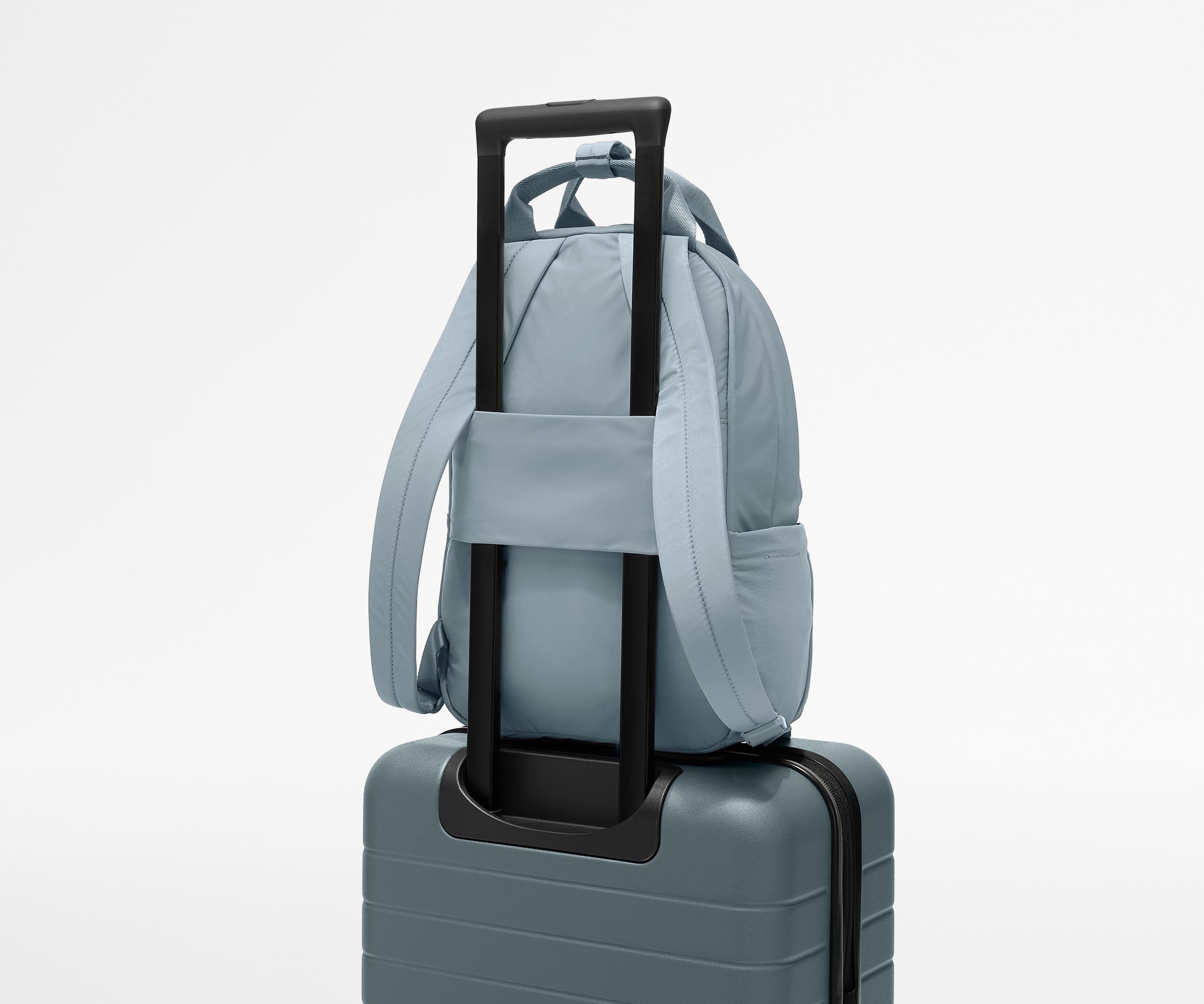 Featherlight Backpack on top of an Away suitcase, attached by the trolley sleeve