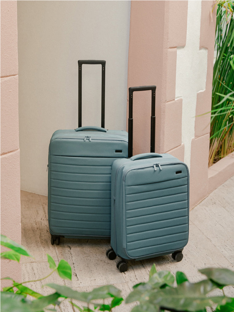 Two Softside suitcases in Coast Blue in front of a building