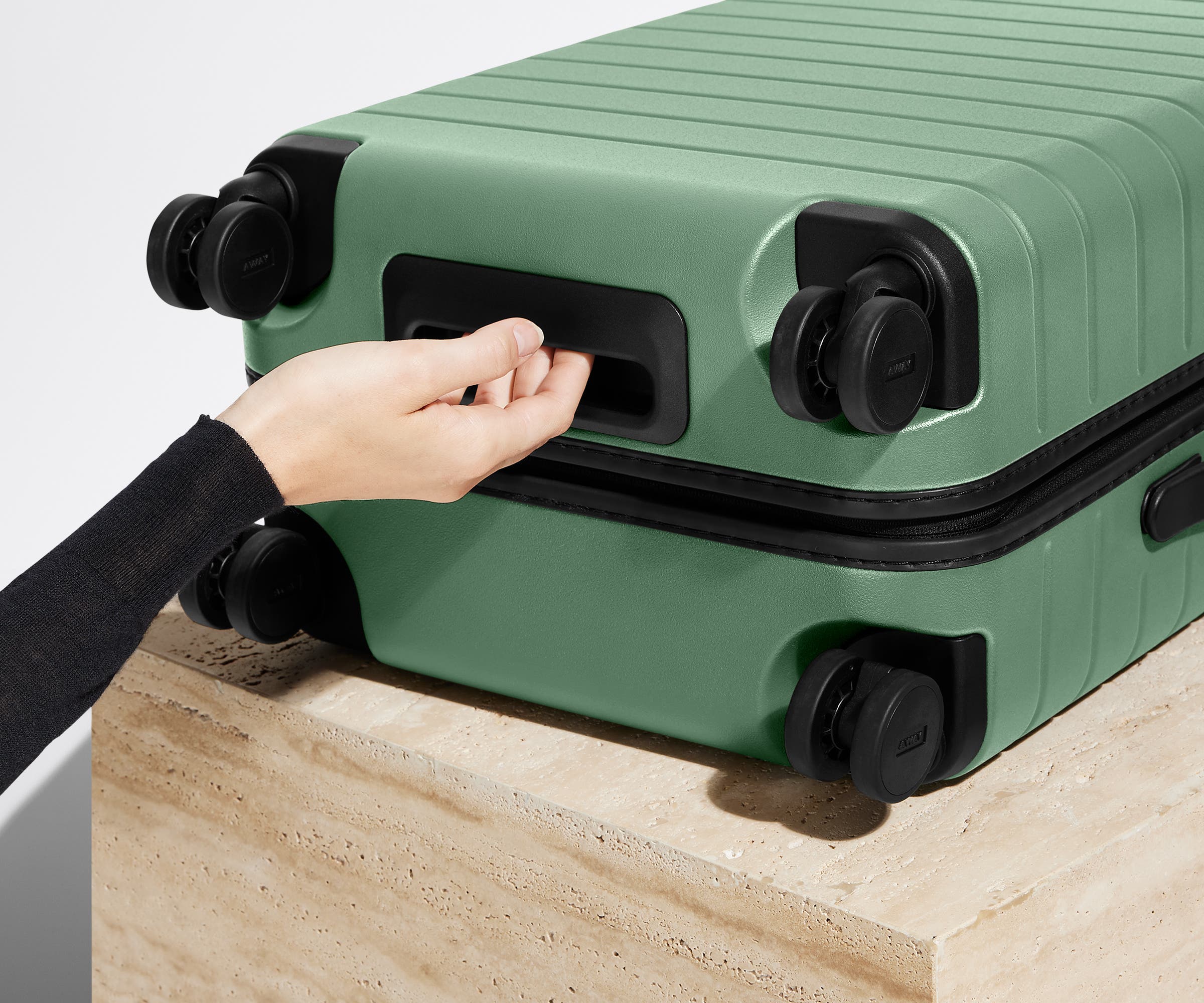 The Bigger Carry-On suitcase in Sea Green shown from below highlighting the underside grab handle