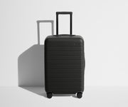 Front product view of The Bigger Carry-On suitcase in Jet Black with raised handle
