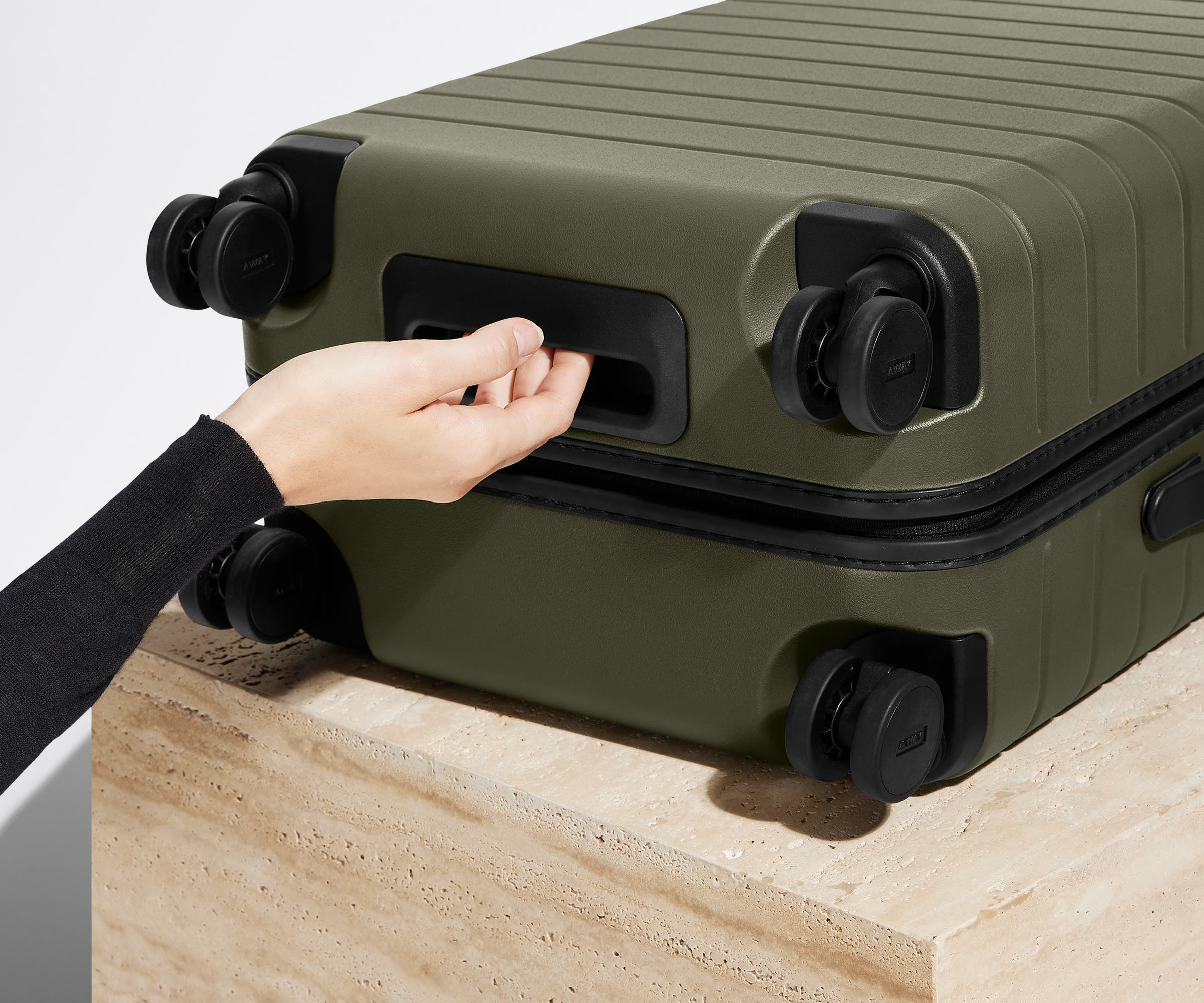 The Bigger Carry-On suitcase in Olive Green shown from below highlighting the underside grab handle