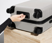 The Bigger Carry-On suitcase in Cloud Gray shown from below highlighting the underside grab handle